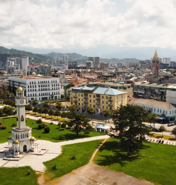 Aerial drone view of Batumi, Georgia. Old and modern buildings, greenery, roads, mountains, cloudy sky