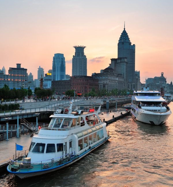Boat in Huangpu River with Shanghai urban architecture at sunset