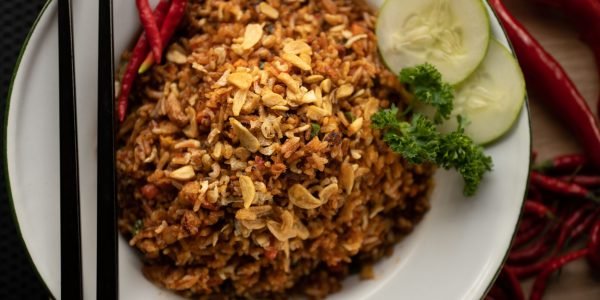 An overhead shot of a dish with rice and sliced vegetable on a round white plate