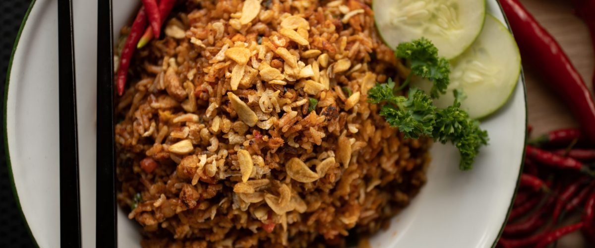An overhead shot of a dish with rice and sliced vegetable on a round white plate