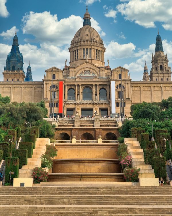 The Palau National in Barcelona, Spain gardens and people in front of it. Cloudy sky