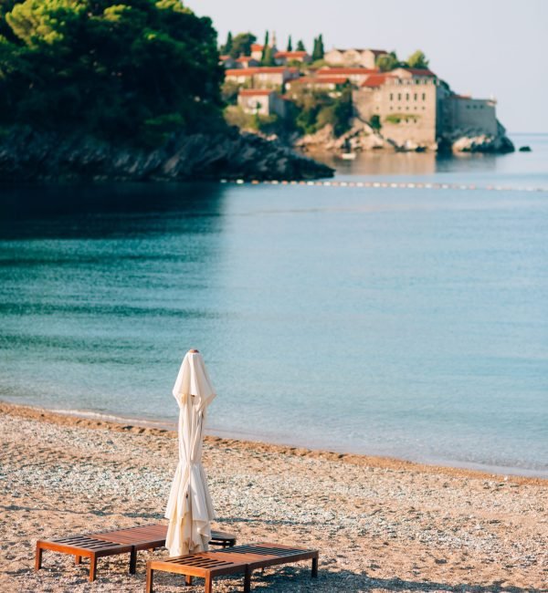 Sun beds and umbrellas on the beach. Montenegrin beaches of the Adriatic Sea. Sveti Stefan beach.